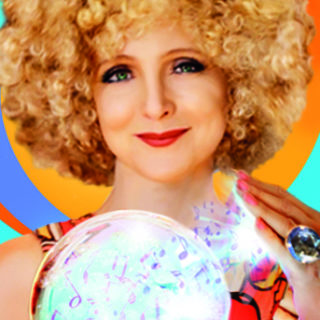 A female with a blonde afro smiling at the camera whilst holding a crystal ball