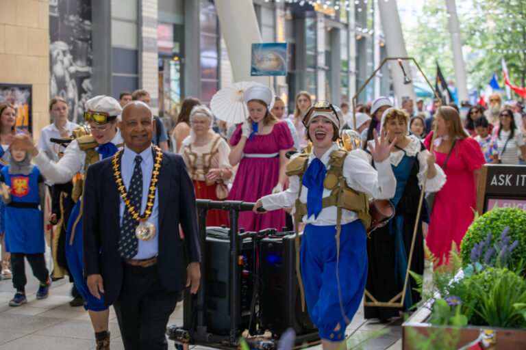 Basingstoke Festival parade 2024. A group of people parade through Festival Place restaurant area.