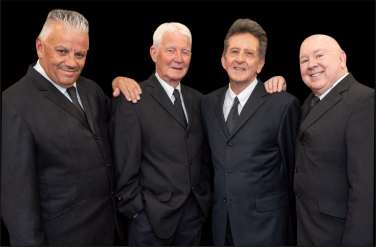 4 men stand wearing suits.