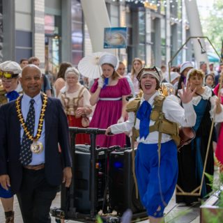 Basingstoke Festival parade 2024. A group of people parade through Festival Place restaurant area.