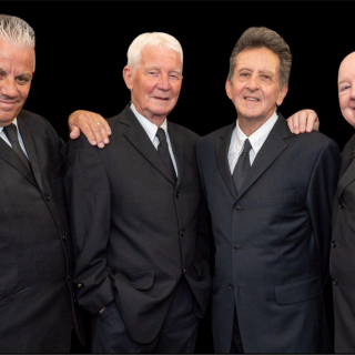 4 men stand wearing suits.